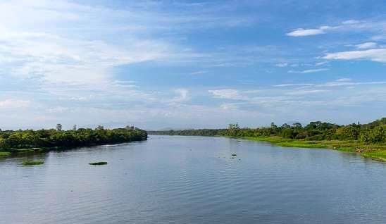 Rio Ribeira largo e calmo, com mata ciliar nas duas margens